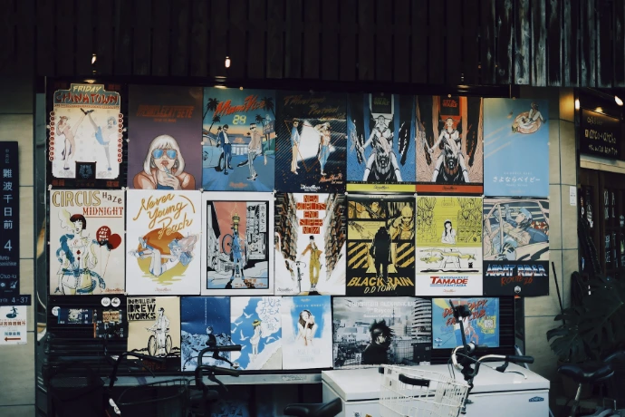 Various posters displayed on a wall outside a shop.